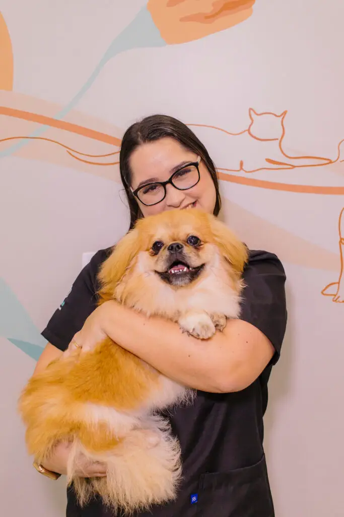 Dra. Carol segurando um cachorro na Clínica Veterinária Amigo Fiel