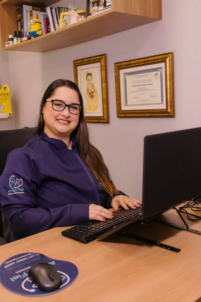 Dra. Carol sentada à mesa com um computador na Clínica Veterinária Amigo Fiel
