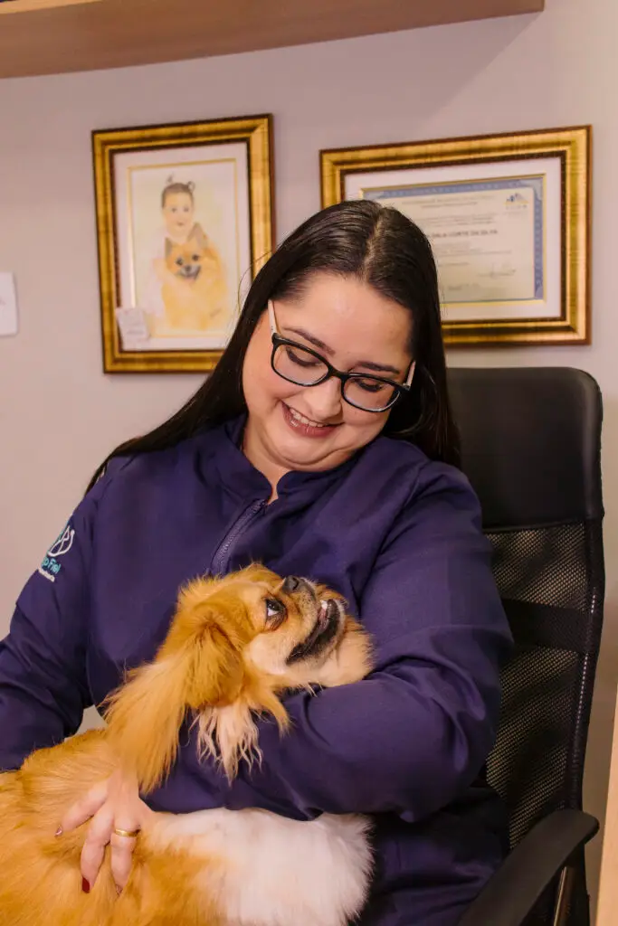 Dra. Carol sentada com um cachorro no colo na Clínica Veterinária Amigo Fiel